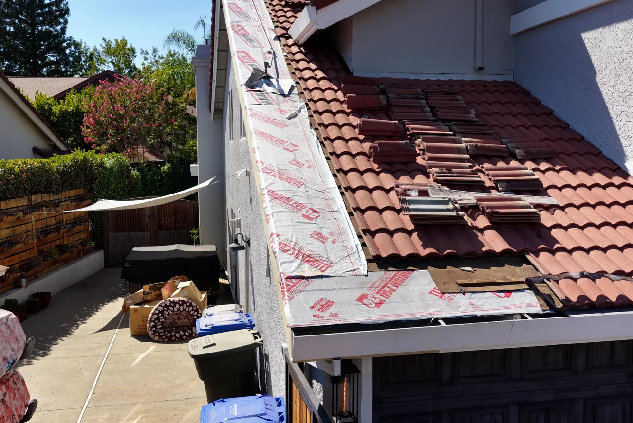 A tile roof replacement in progress with new underlayment down and tiles staged
