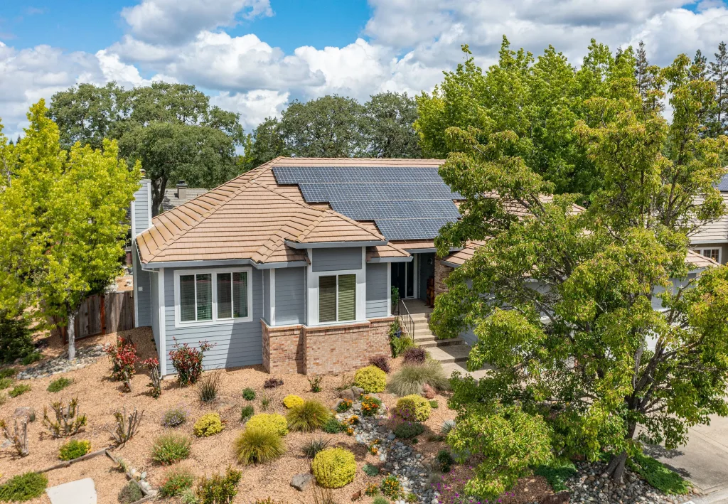 Home surrounded with landscaped vegetation and solar panels on the roof.