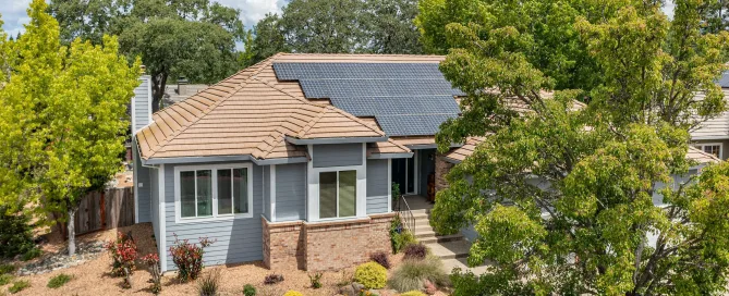House with new roof and solar surrounded by trees.