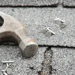 hammer and nails on a broken shingle roof