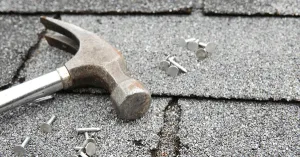 hammer and nails on a broken shingle roof